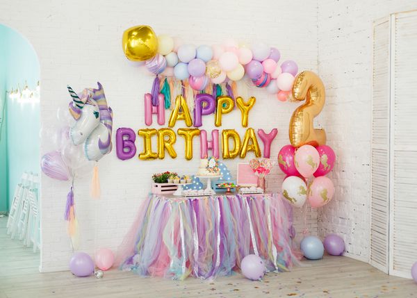 دکوراسیون اتاق برای کودکان amp x27؛ s تولد با تکشاخ یک میز با شیرینی روی زمینه دیوارهای آجری سفید قرار دارد باتلاق کیک کیک زغال اخته با خامه شکلات گل گل کلوچه