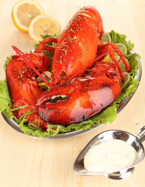 خرچنگ قرمز روی بشقاب با سبزیجات روی میز چوبی نزدیک
