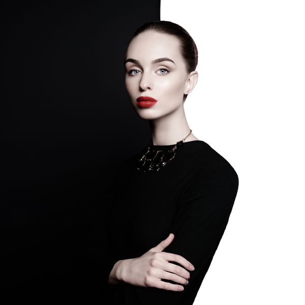 بانوی جوان با جواهرات سیاه شیک در استودیوی سیاه و سفید زن زیبایی با لب های کامل و رژ لب قرمز در فتوشیمیایی قرار دارد پرتره مد مدل شیک