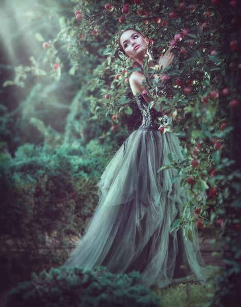 مدل لباس عاشقانه زیبایی دخترانه که در درختان باغ قرار می گیرد از طبیعت در باغ سیب لذت می برد زن جوان زیبا در باغ فانتزی لباس بلند پرتره با طول کامل در فضای باز افسانه