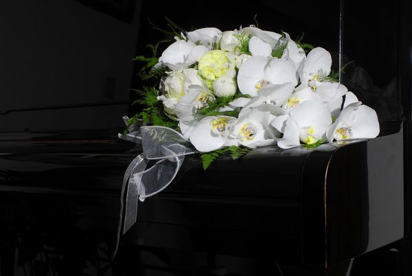 دسته گل عروسی زیبا که با گلهای سفید روی پیانو سیاه ساخته شده است