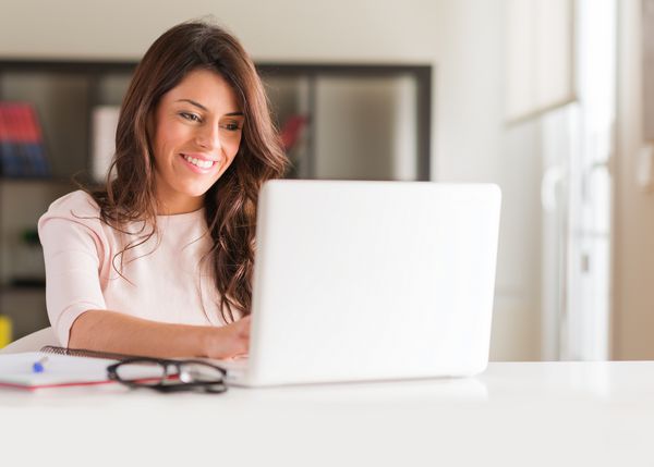 زن زیبا و جوان مبارک با استفاده از لپ تاپ در داخل خانه