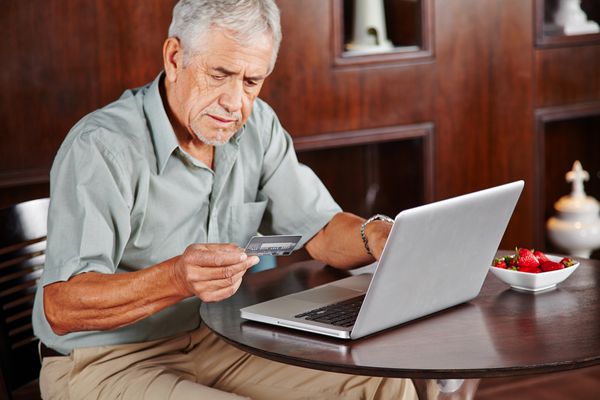مرد ارشد در لپ تاپ با پرداخت کارت اعتباری برای خرید آنلاین