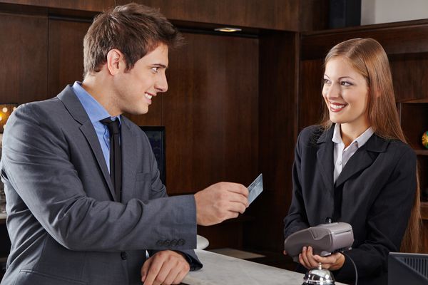 مدیر کسب و کار در پذیرش هتل با کارت اعتباری پرداخت می کند