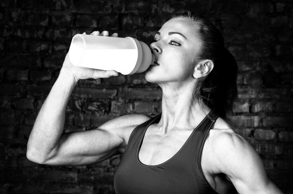 زن قوی در حال نوشیدن تغذیه ورزشی است