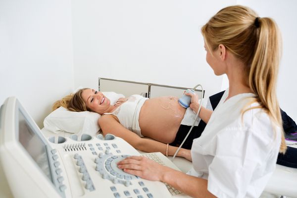 زن باردار جوان که از سونوگرافی از پزشک زن در کلینیک استفاده می کند