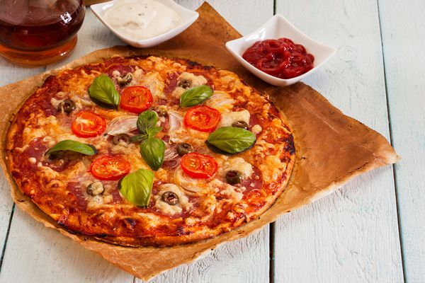 پیتزا با سالامی گوجه فرنگی و زیتون روی میز