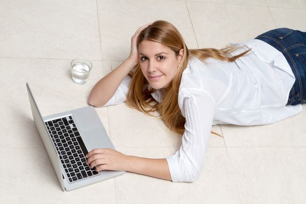 زن جوان تجاری که روی لپ تاپ روی زمین کار می کند