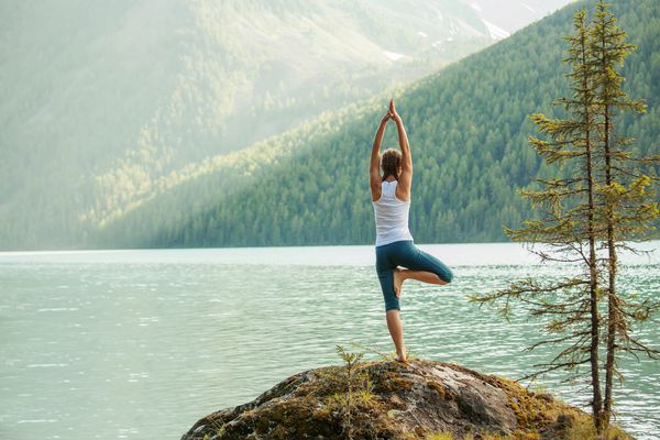 زن جوان مشغول تمرین یوگا در دریاچه کوه است