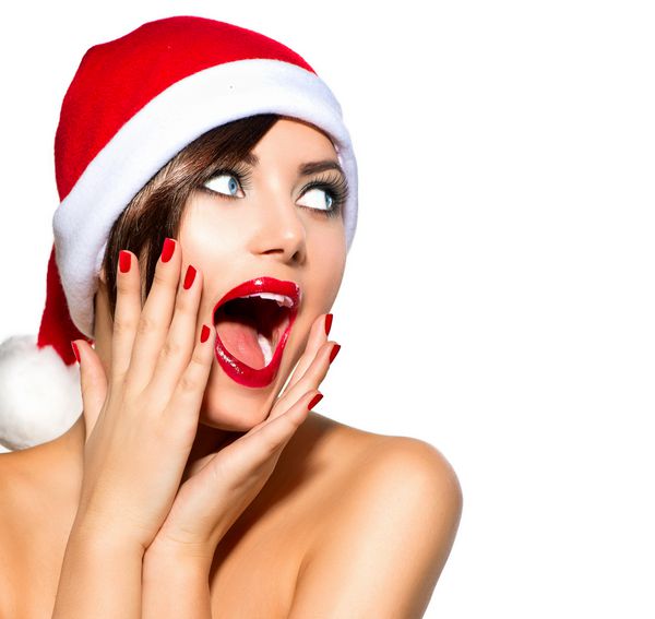 زن کریسمس دختر مدل زیبایی در سانتا کلاه جدا شده در زمینه سفید خنده دار خنده دار پرتره زن دهان باز احساسات واقعی لب و مانیکور قرمز آرایش تعطیلات زیبا