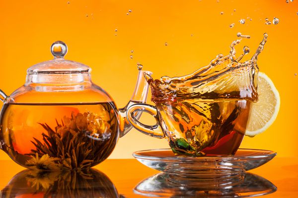فنجان چای را روی لیوان با زمینه نارنجی قرار دهید