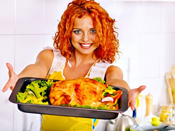 زن جوان در حال آشپزی مرغ در آشپزخانه