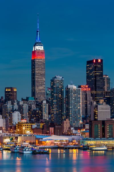 WEEHAWKEN NJ ایالات متحده آمریکا 17 فوریه 2014 ساختمان امپراتوری ایالتی در غروب بالای آسمان خراش نمادین ​​به افتخار روسای جمهور رنگ های پرچم آمریکا آبی-سفید-قرمز را به نمایش می گذارد و amp x27؛ روز