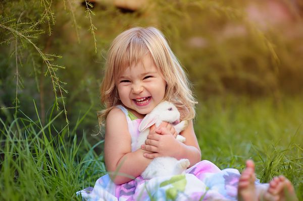 دختر بچه ناز با یک خرگوش اسم حیوان دست اموز دارای یک عید پاک در زمینه چمن سبز است