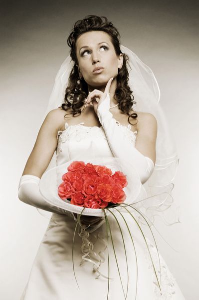 عروس متفکر با دسته گلهای بیش از زمینه خاکستری