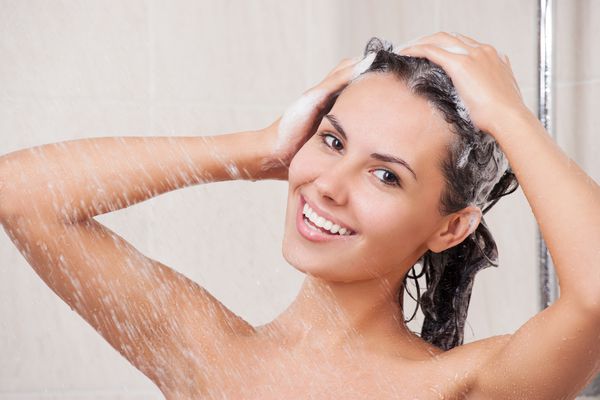 زن جوان با شامپو سر خود را در حمام می شست