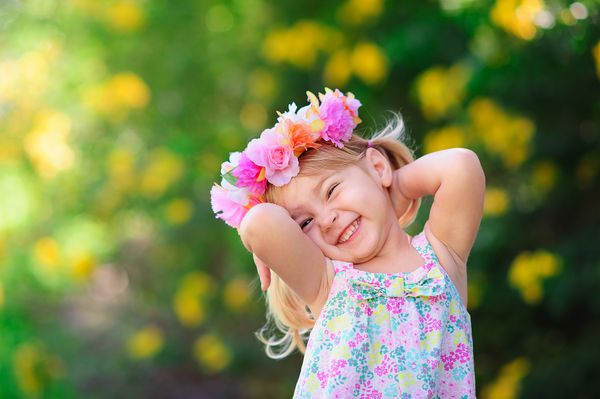کودک خندان با گل در روز تابستان در فضای باز