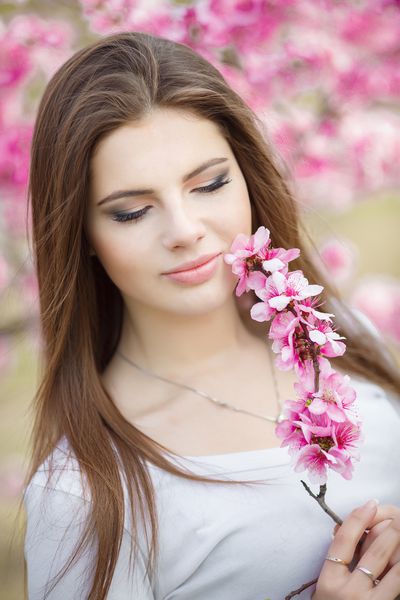 دختر جوان زیبا در گل های بهاری پرتره سبک زندگی در باغ دختر نوجوان مبارک در پارک بهاری که از طبیعت لذت می برد زمان بهار سلسله