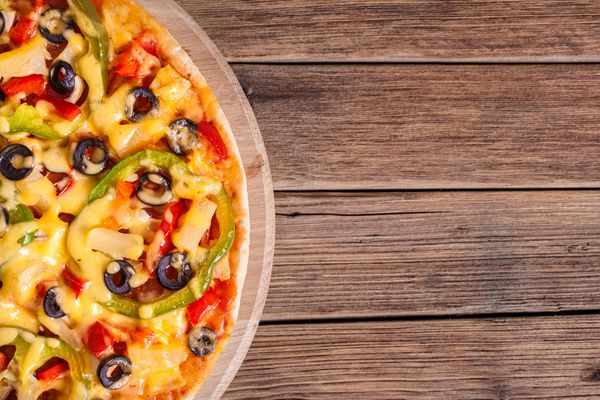 پیتزا خوشمزه ایتالیایی که روی میز چوبی سرو می شود