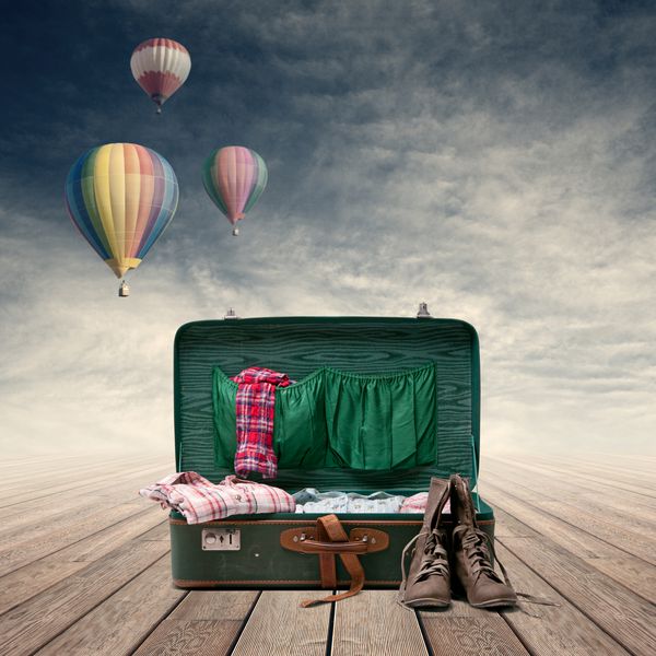 چمدان اکسپلورر با لباس و چکمه بالن هوا در زمینه