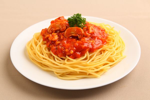 اسپاگتی را با سس گوجه فرنگی روی بشقاب سفید بچینید