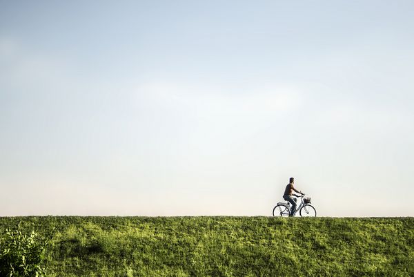 مردی که در یک منظره سبز و خالی دوچرخه سوار می شود