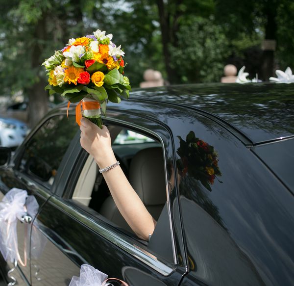 فقط یک زن و شوهر با هم در یک ماشین ازدواج کردند عروس مبارک نگه داشتن گل های عروسی تمرکز روی گلها