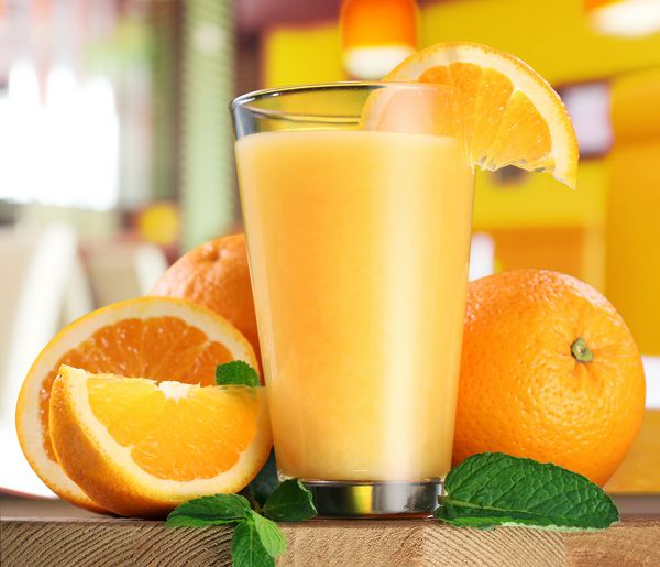 میوه های پرتقال و لیوان آب پرتقال روی میز چوبی