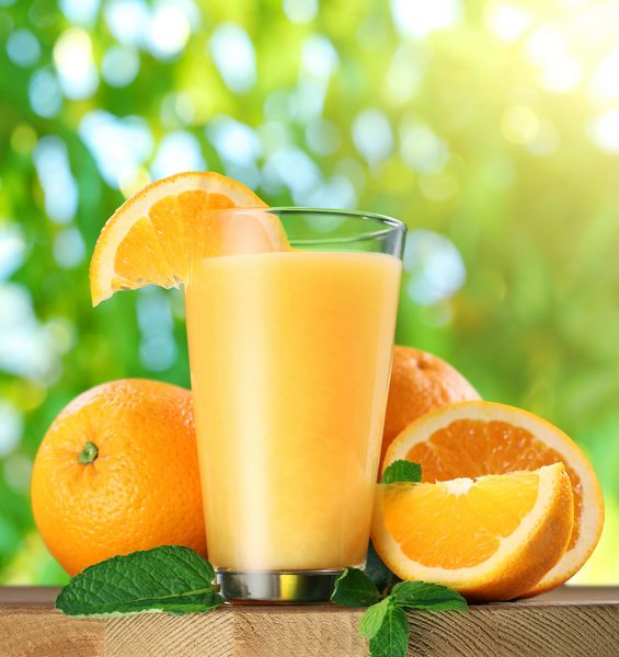 میوه های پرتقال و لیوان آب پرتقال روی میز چوبی