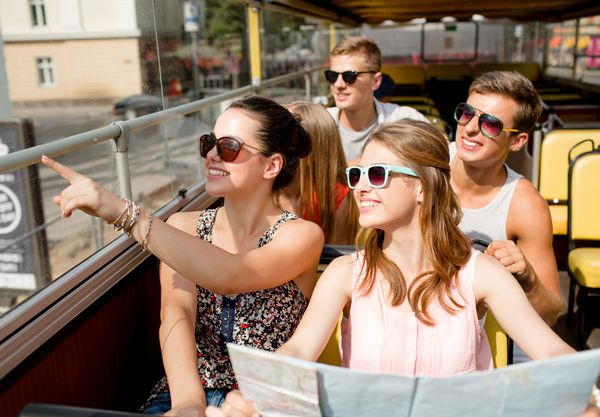 دوستی مسافرت تعطیلات تابستان و مفهوم مردم گروهی از دوستان لبخند با نقشه سفر با اتوبوس تور