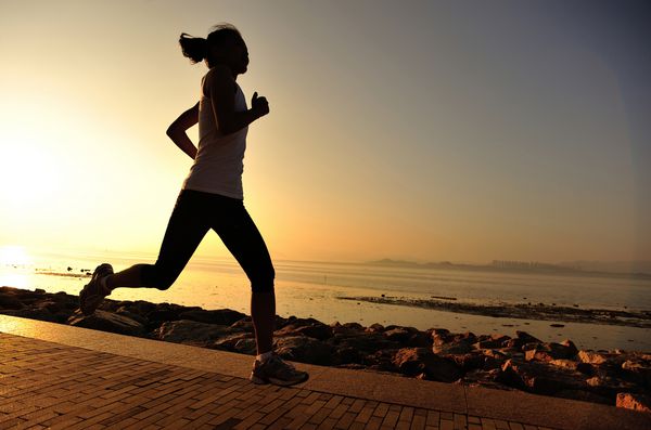 ورزشکار دونده در حال دویدن در کنار دریا است مفهوم سلامتی تمرین شبح تناسب اندام زن آفتاب طلوع آفتاب