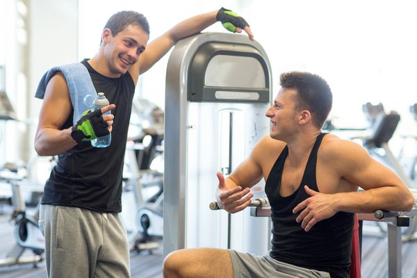 ورزش تناسب اندام تجهیزات شیوه زندگی و مفهوم مردم مردان لبخند زده با بطری آب که در دستگاه بدنسازی ورزش می کنند