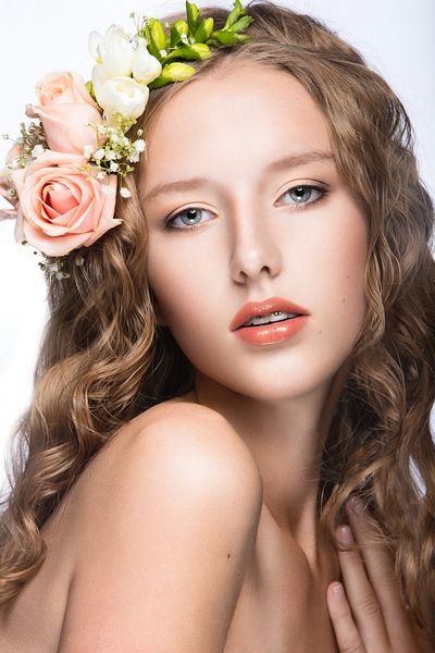 دختری زیبا با پوست کامل و تاج گل های روشن روی سرش تصویر گرفته شده در استودیو با پس زمینه سفید