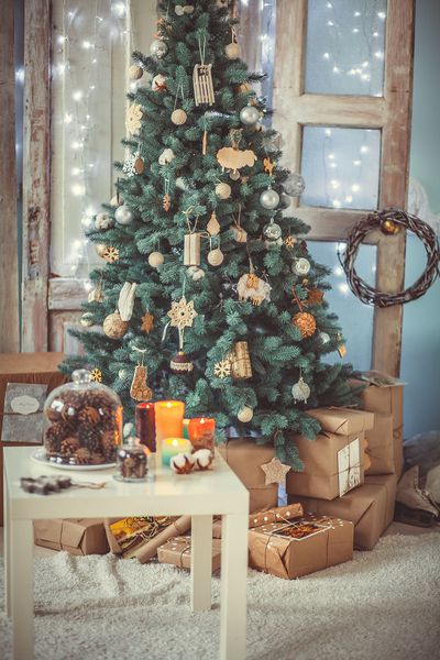 تزئین درخت کریسمس و جعبه های هدیه در اتاق نشیمن