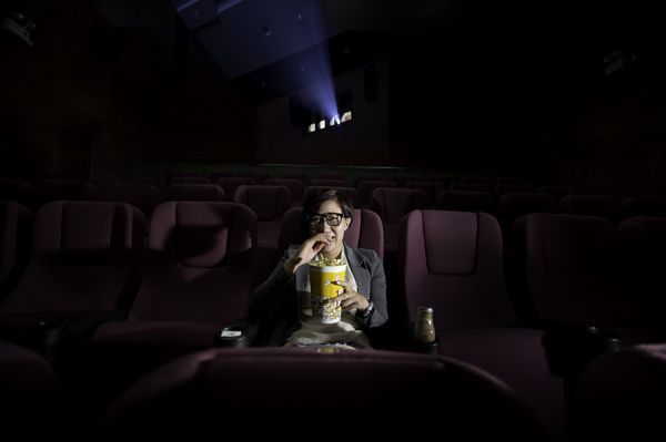 دختری جوان هنگام تماشای فیلم در حال خوردن پاپ کورن است