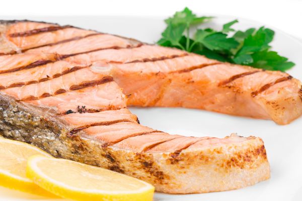 استیک ماهی کباب شده با سبزیجات روی بشقاب پس زمینه کامل