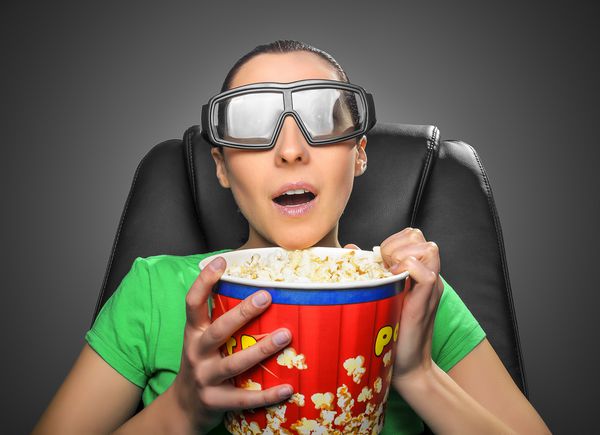 بیننده در تماشای سینما سه بعدی در عینک با کاسه پر از پاپ کورن