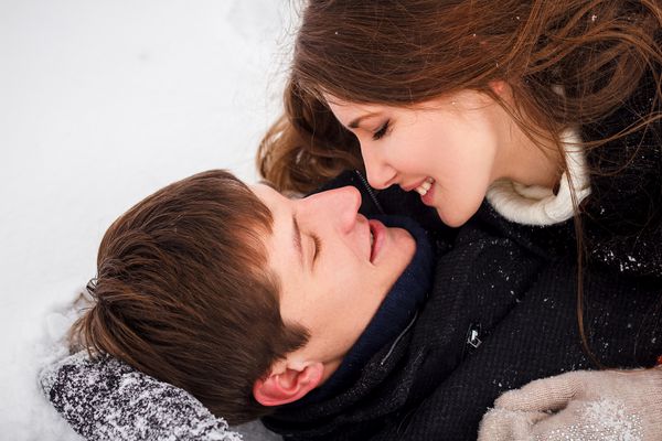 زن و شوهر جوان در حال بوسیدن در برف هستند