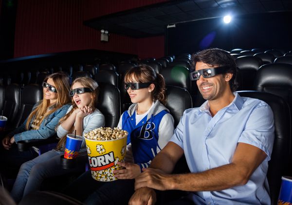 خانواده چهار نفره شاد در هنگام تماشای فیلم سه بعدی در سینمای سینما