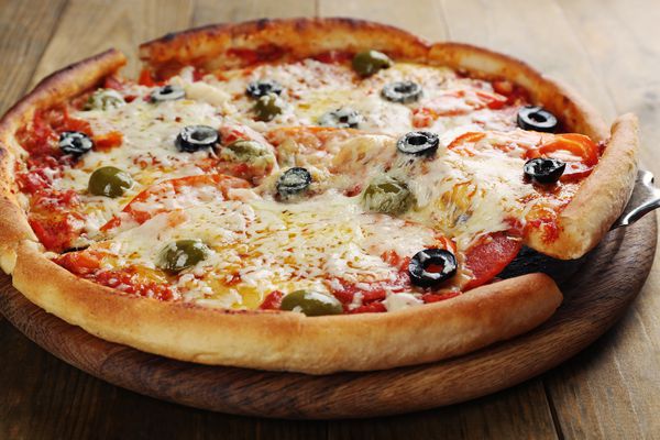 پیتزا با پنیر روی صفحه و زمینه چوبی میز
