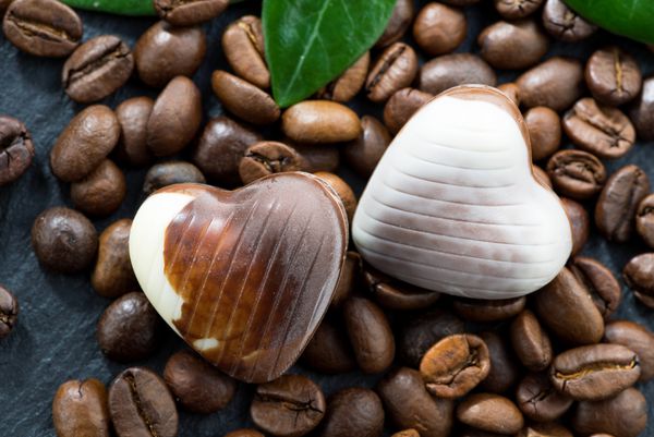 دانه های قهوه و شکلات های شکلاتی به شکل قلب کلوزآپ افقی
