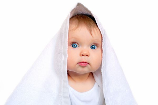 کودک چشم آبی پس از حمام زیر حوله سفید جدا شده بر روی زمینه سفید