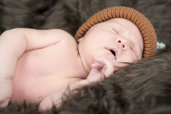نوزاد تازه متولد شده با کلاه رنگی می خوابد