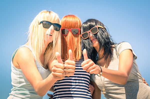 گروهی از دوست دختران جوان با تمرکز بر روی موهای خنده دار رنگی و عینک آفتابی مفهوم دوستی و سرگرمی در تابستان با بیان مثبت با انگشت شست بهترین دوستان مشترک شادی