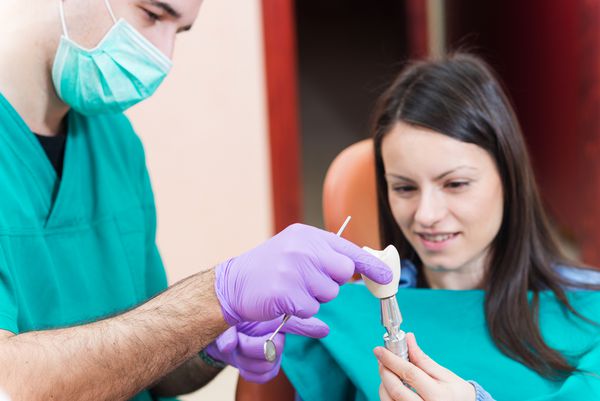 دندانپزشک کاشت دندان با تاج را به بیمار خود نشان می دهد