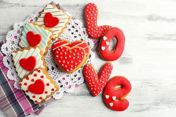 کوکی های شکل قلب برای روز ولنتاین در دستمال روی زمینه چوبی رنگی