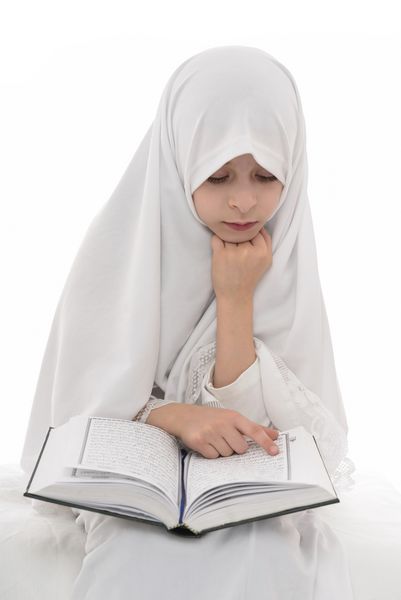 دختر بسیار زیبا مسلمان که کتاب مقدس قرآن را می خواند و از پس زمینه سفید جدا شده است