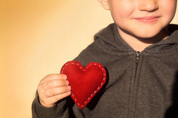 قلب قرمز در دست کودک مفهوم مهربانی هدیه ولنتاین دست ساز بستن افقی فضای کپی