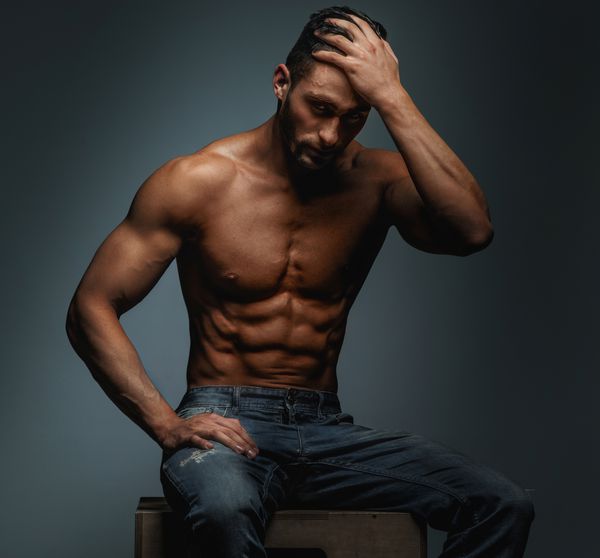 مرد عضلانی بدون شلوار با شلوار جین آبی جدا شده در زمینه خاکستری