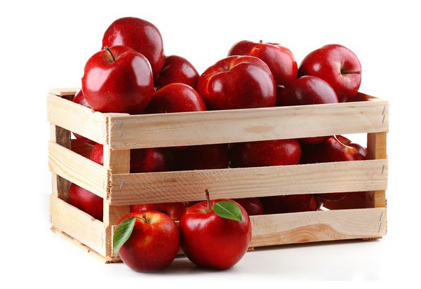 سیب های قرمز در جعبه چوبی بر روی رنگ سفید جدا می شوند